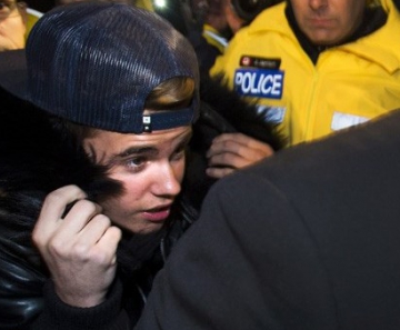 Justin Bieber é cercado por policiais e jornalistas ao se apresentar à polícia em fevereiro.