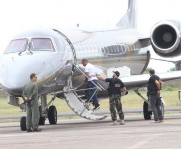 O traficante, de camiseta branca, embarcou em uma aeronave da Polícia Federal sob um forte esquema de segurança